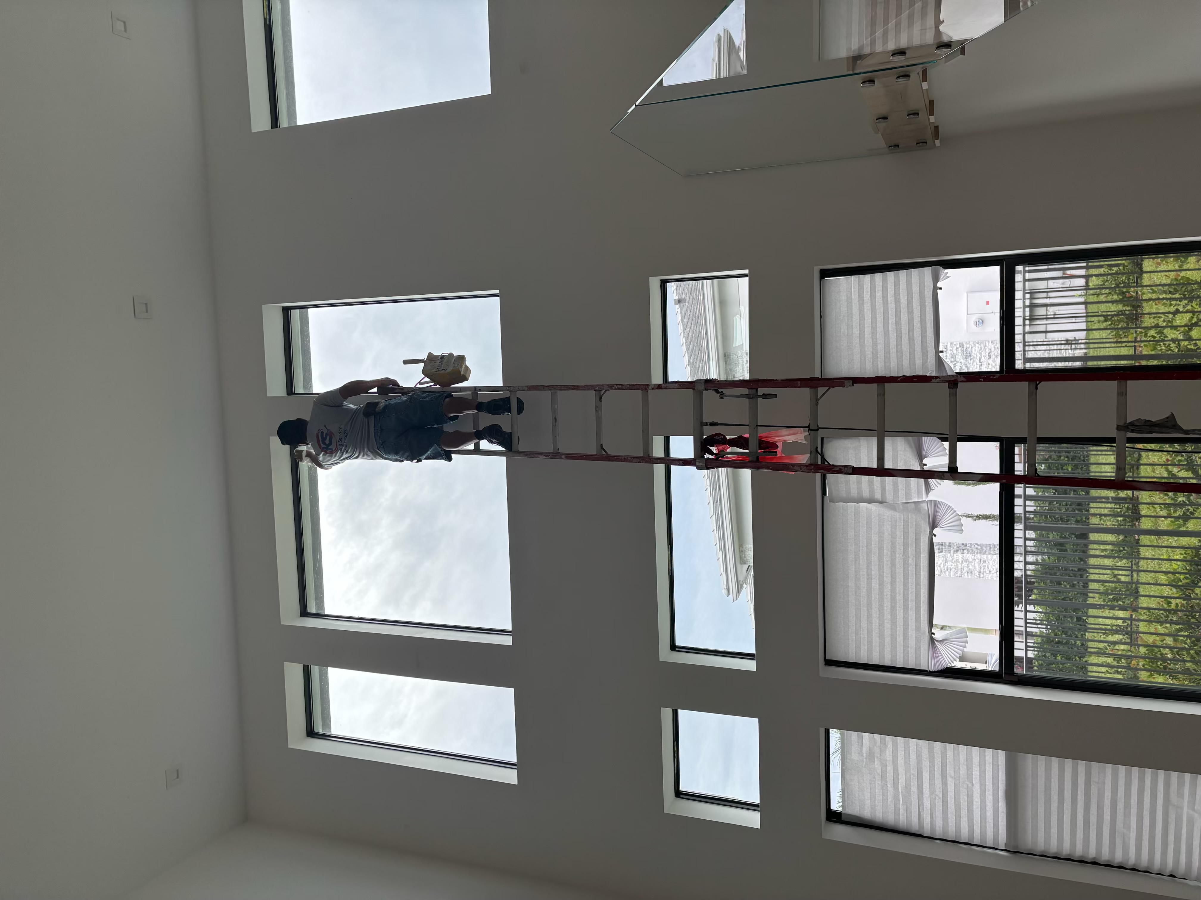 Painter working near a tall interior window wall
