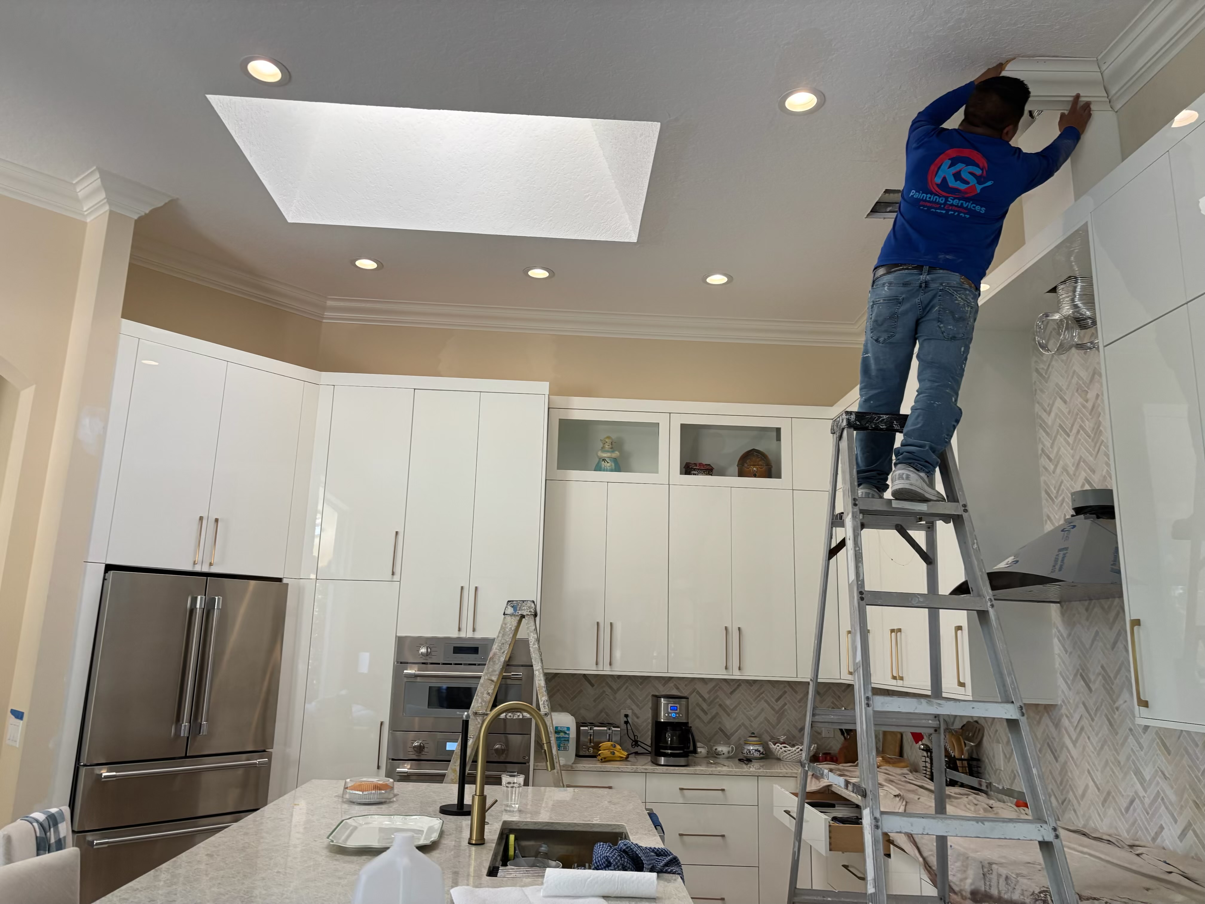 Painter working on kitchen ceiling trim detail